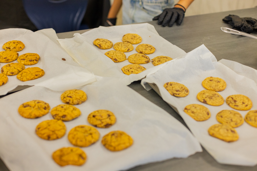 Dozens of golden, freshly baked chocolate chip cookies cooling on paper towels across a table