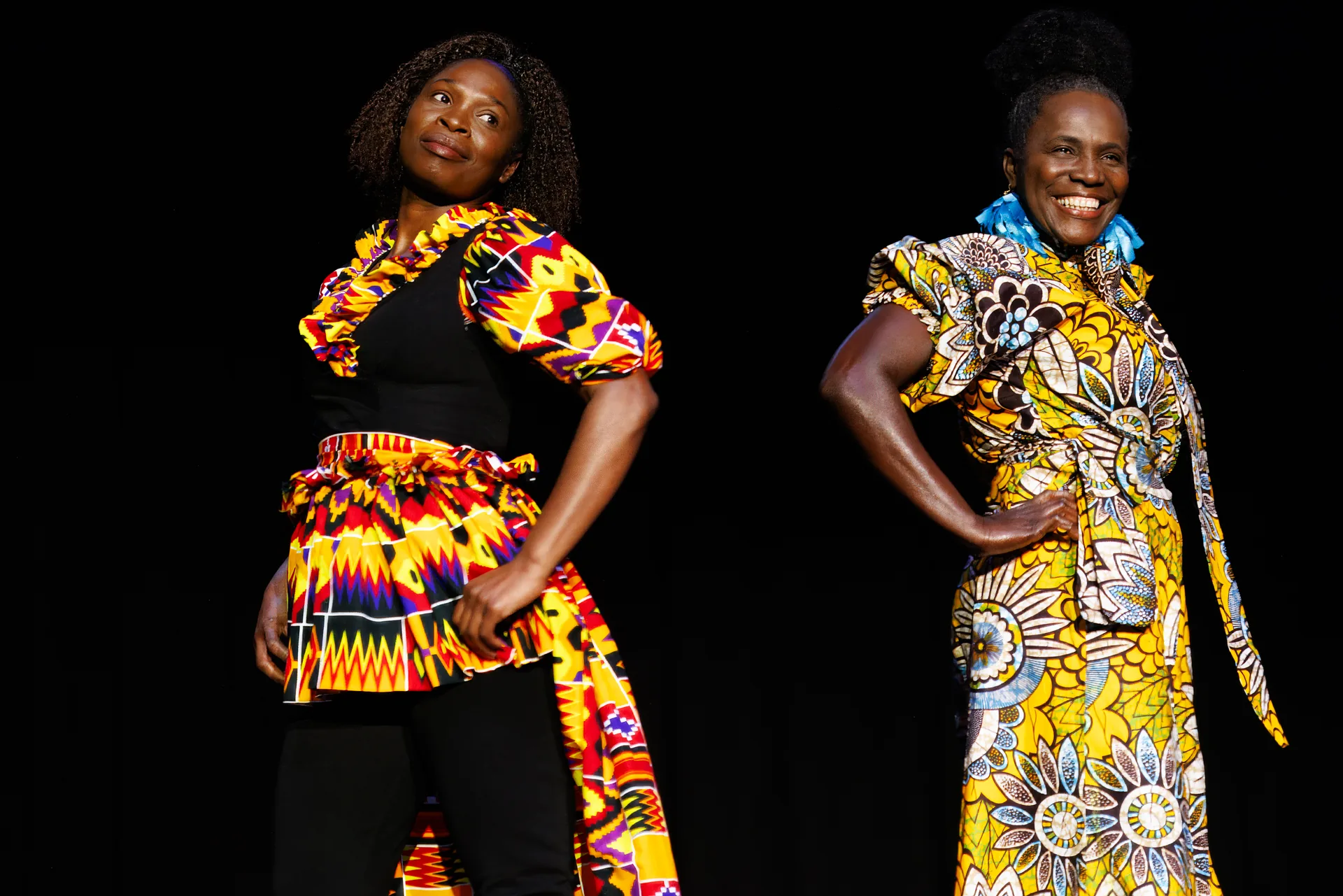 Two women modeling vibrant Kente and floral African print garments