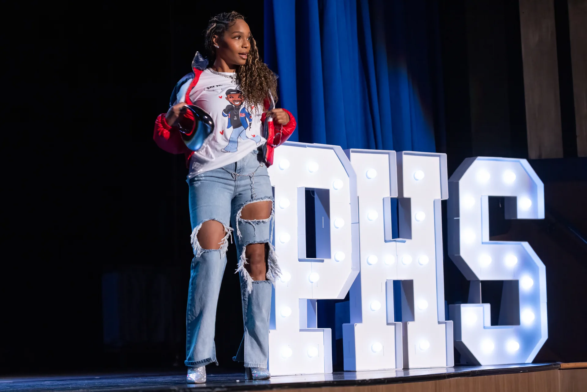 Student walking the runway in front of illuminated PHS letters